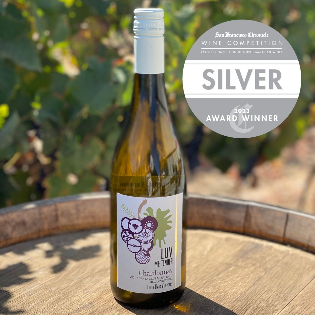 bottle of LUV chardonnay on a wine barrel with silver award badge