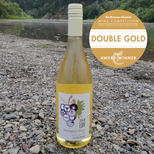 bottle of LUV Sauvignon Blanc on the bank of a stream with the double gold award badge over image